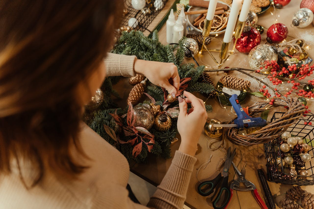 services-03 Woman arranging Christmas decorations on a wreath, crafting holiday decor.
