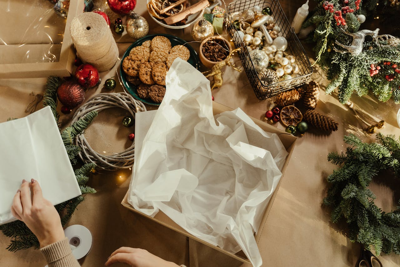 journey Hands preparing holiday gifts with cookies and decorations in a Christmas workshop setting.