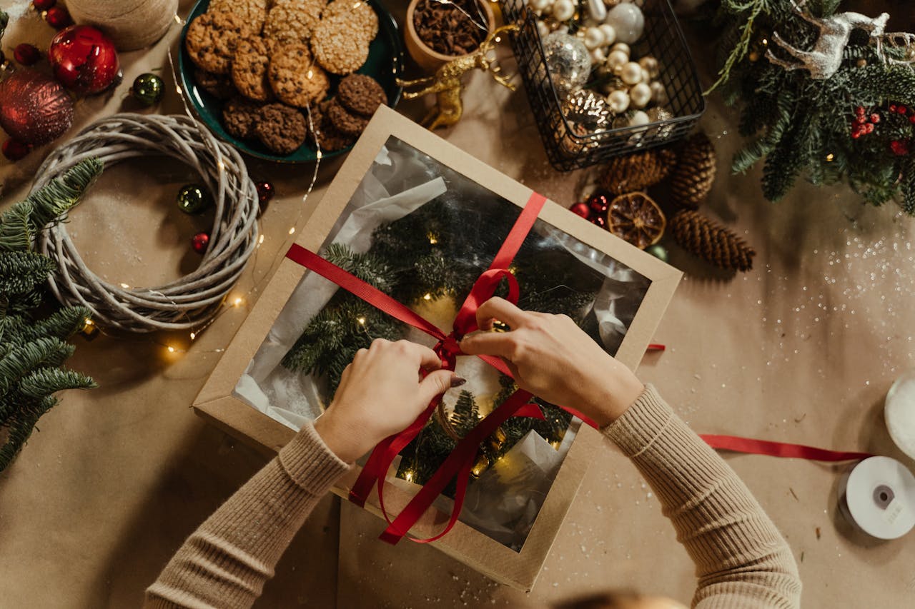 Top view of a Christmas gift wrapping scene with cookies, baubles, and festive decorations.